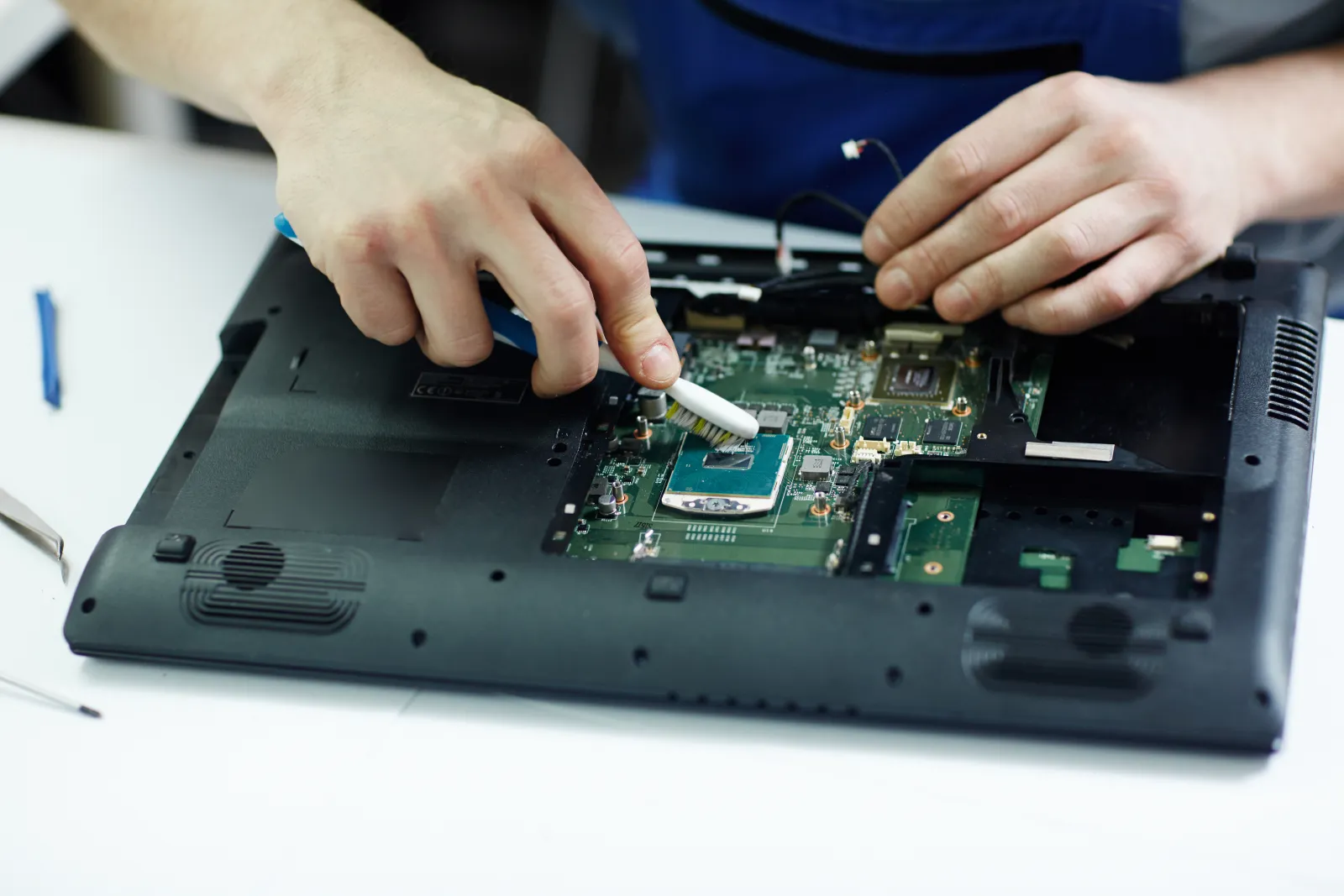 Técnico limpando a placa de um notebook desmontado